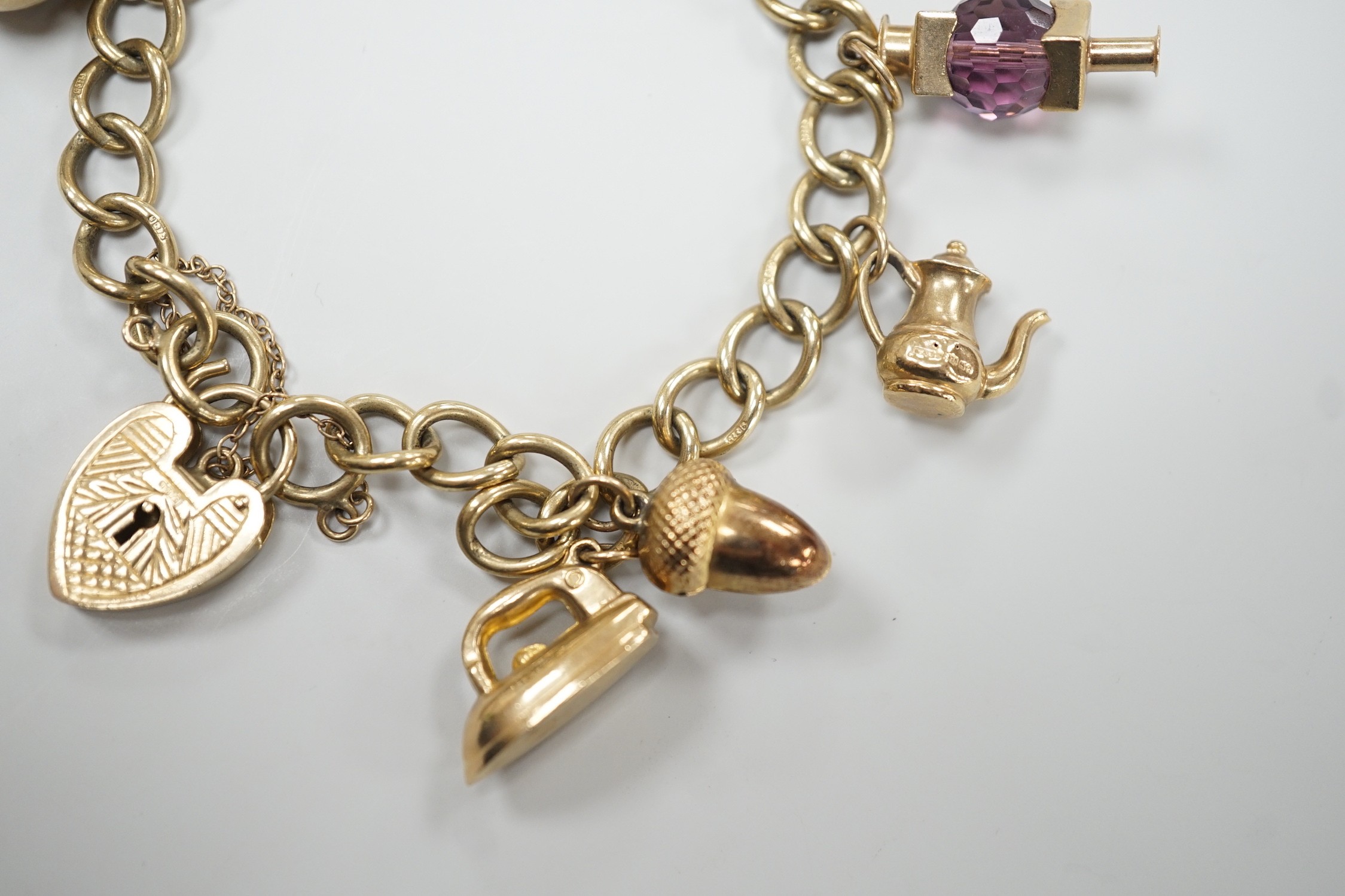 A 9ct gold oval link charm bracelet, hung with ten assorted charms including nine 9ct gold, gross weight 31.9 grams.